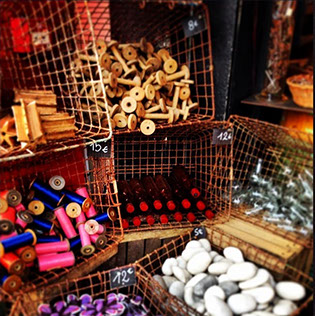 Miscellaneous flea market finds organized and for sale within wire baskets placed on their side. Found in flea market in Paris, France.
